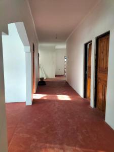 an empty hallway of an empty house with a floor and wooden doors at Mambo Leo Hostel in Paje