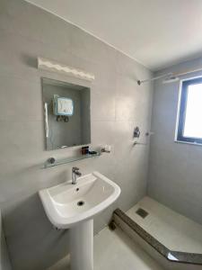 W białej łazience znajduje się umywalka i lustro. w obiekcie YULOKO GUEST HOUSE w Katmandu