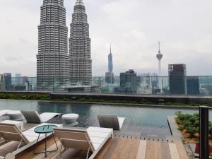 un patio en la azotea con sillas y una piscina con vistas al perfil urbano. en Star Sky Park KLCC en Kuala Lumpur