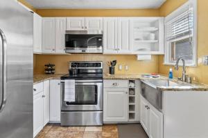 kuchnia z białymi szafkami i urządzeniami ze stali nierdzewnej w obiekcie West End Stay w mieście Boise