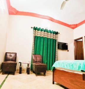 a bedroom with a green curtain and two chairs at Gulshan Palace Near Millennium Mall Agha khan Hospital Airport Karachi in Karachi