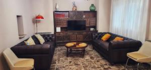 a living room with two leather couches and a television at Casa Tío Peguero, Piscina Climatizada in San Bartolomé de Pinares