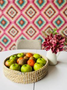 une corbeille de fruits sur une table à côté d'un vase avec une fleur dans l'établissement Hanul Fullton, à Cluj-Napoca