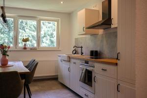 een keuken met witte kasten en een tafel en raam bij Ferienwohnung Holiswald in Oppenau