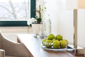 a table with a bowl of green apples on it at Hotel Mecklenburger Hof Gnoien in Gnoien
