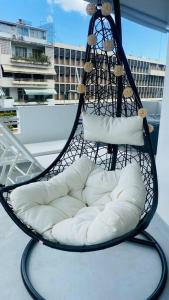een hangstoel met witte kussens op een balkon bij Urban Zen Appart Spacieux studio atypique avec bain a remous proche de tout in Pointe-à-Pitre