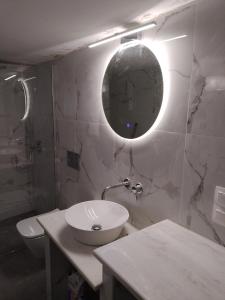 Kallithea Deluxe في ميتيليني: حمام أبيض مع حوض ومرآة