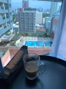 a cup of coffee sitting on a table next to a window at Comfy Condo Grand Riviera Suite, Roxas Blvd Ermita Manila infront of US Embassy in Manila