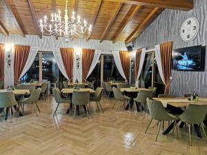 a dining room with tables and chairs and a clock at POPASUL LU' VODĂ in Borşa