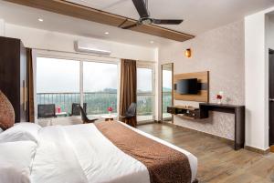 een hotelkamer met een groot bed en een televisie bij WOLKENBURG RESORT & SPA in Munnar