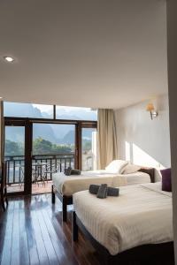 a hotel room with three beds and a balcony at Silver Naga Hotel in Vang Vieng