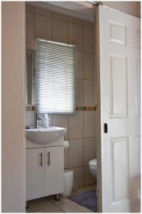 un bagno con lavandino, water e finestra di GRACE'S PLACE a Beaufort West