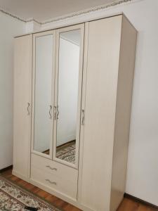 a white cabinet with mirrored doors in a room at Квартира in Atyraū