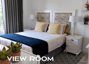 um quarto com uma cama grande, um cobertor azul e almofadas. em Hadeda Hall em Joanesburgo