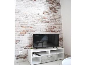 een televisie op een witte stand voor een stenen muur bij Studio style urbain "Cottage de Moissac" in Moissac