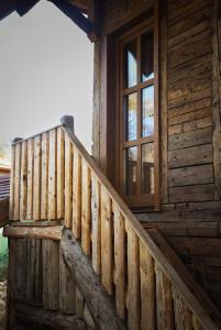 a wooden staircase leading up to a cabin with a window at Székelyföld,Siklódi Kő Vendégház Szénatároló in Bartoştana