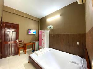 a bedroom with a bed and a table and a refrigerator at Thu Đô Motel in Vung Tau