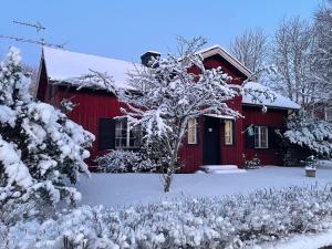 a red barn covered in snow with a yard at Lilla Röda Huset. in Sjötofta