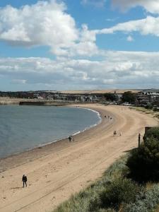 a beach with people walking on the sand and the water at Beachfront Treasure in Musselburgh