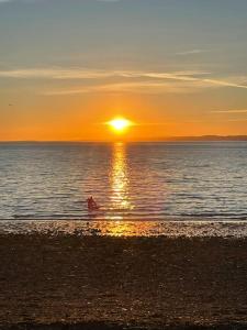 une personne dans l'eau à la plage au coucher du soleil dans l'établissement Beachfront Treasure, à Musselburgh
