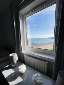 Cette chambre dispose d'une fenêtre et d'une table avec une lampe. dans l'établissement Beachfront Treasure, à Musselburgh