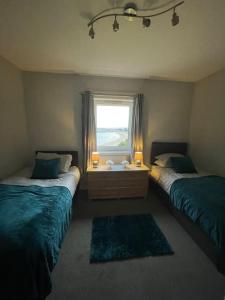 a bedroom with two beds and a window with two lamps at Beachfront Treasure in Musselburgh