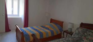 - une chambre dotée d'un lit avec une couverture rayée bleue et jaune dans l'établissement GITE DE LA COMBE BASSE, à Le Masnau-Massuguiès