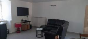 un salon avec une chaise noire et une télévision dans l'établissement GITE DE LA COMBE BASSE, à Le Masnau-Massuguiès