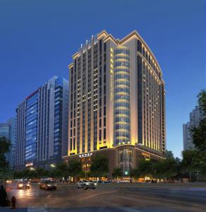 Guangzhou Victoria Hotel في قوانغتشو: مبنى كبير فيه سيارات في مواقف