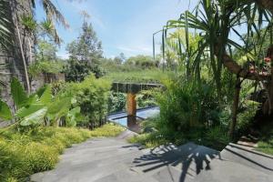 un jardín con un puente y algunas plantas en Chameleon Villa Bali en Tabanan