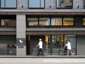 two people walking their bikes in front of a store at Dhawa Yura Kyoto in Kyoto
