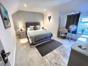 a bedroom with a bed and a chair and a window at Anchor Cottage - beautiful two bedroom cottage in the heart of Holt in Holt