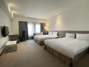 a hotel room with two beds and a television at Guide Hotel Hsinchu Zhongyang in Hsinchu City