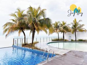 a swimming pool with palm trees and the ocean at SilverScape Residence I Luxury 2-4 BR I 6-11 pax I Bathtub I Seaview I Infinity Pool I Jonker St I City Centre by Jay Stay Management in Melaka