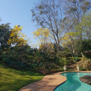 a swimming pool with a brick walkway around a yard at 18 Pioneer Kloof in Kloof