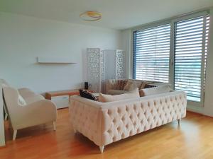 een woonkamer met een grote witte bank en stoelen bij Near Lake Two Bedroom Duplex Apartment in Wenen