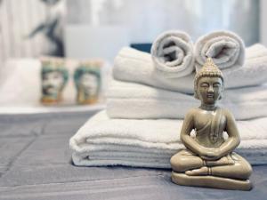 a statue of a buddha sitting next to a stack of towels at I Cinque Mori DEVA in Siracusa