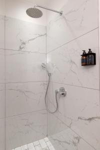 a bathroom with a shower with white marble walls at Glow Boutique Suites in Hermanus