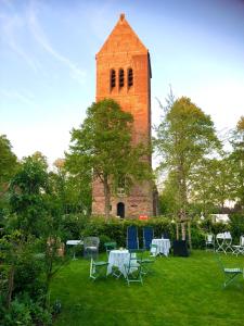 una torre con mesas y sillas frente a un edificio en Theetuin en B & B 'De Theetuin', en Wijckel