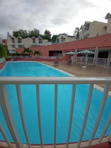 vistas a la piscina desde el balcón de un hotel en STUDIO ROUGE GORGE TARTANE en La Trinité
