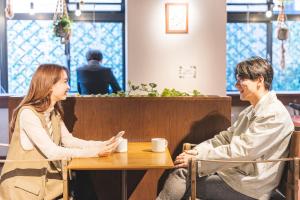 un hombre y una mujer sentados en una mesa en una cafetería en HOTEL RELIEF Namba Daikokuchou, en Osaka