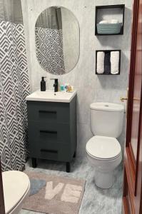 een badkamer met een toilet, een wastafel en een spiegel bij Piso Confort y Detalles Ourense in Ourense