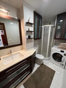 a bathroom with a sink and a washing machine at Piso Confort y Detalles Ourense in Ourense