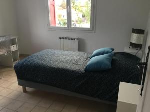 Un dormitorio con una cama con almohadas azules y una ventana en L olivier, en Prades