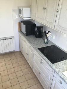 eine Küche mit weißen Schränken und einer schwarzen Mikrowelle in der Unterkunft L olivier in Prades