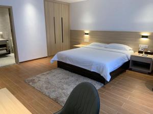 una camera con un letto e una sedia di Guangzhou Fangyuan Hotel a Canton