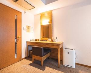 Habitación con escritorio con silla y espejo. en HOTEL RELIEF Namba Daikokuchou, en Osaka
