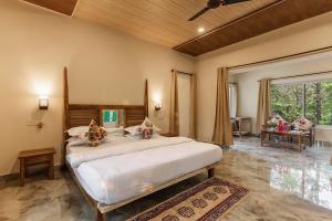a bedroom with a large white bed in a room at Jungle King Resort in Kānha