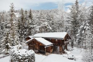 una cabaña en el bosque con nieve en el techo en Hotel Chalet Corso, en San Vigilio Di Marebbe