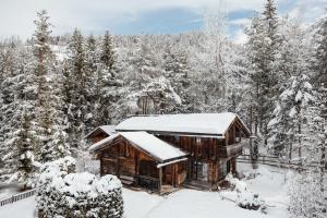 uma cabana na floresta com neve no telhado em Hotel Chalet Corso em San Vigilio Di Marebbe